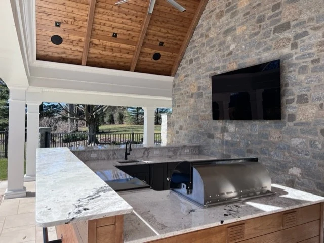 Outdoor television and ceiling speakers in a covered pool-house entertainment area